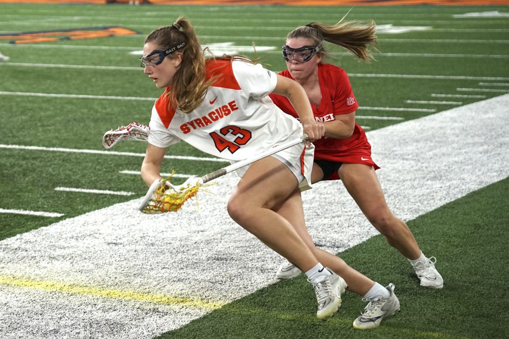 Syracuse's Sierra Cockerille (43) drives forward under pressure from the Cornell defense during a women's lacrosse game Tuesday, March 28, 2023 at JMA Wireless Dome.