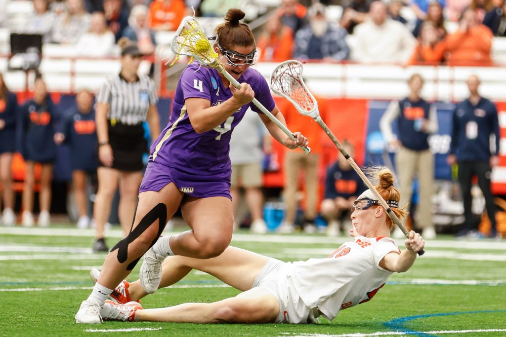 James Madison's Tai Jankowski (4) avoids falling after clashing with Syracuse's Maddy Baxter (49) during the NCAA Tournament quarterfinal on Thursday, May 18, 2023 at JMA Wireless Dome. Photo by Kayla Breen.