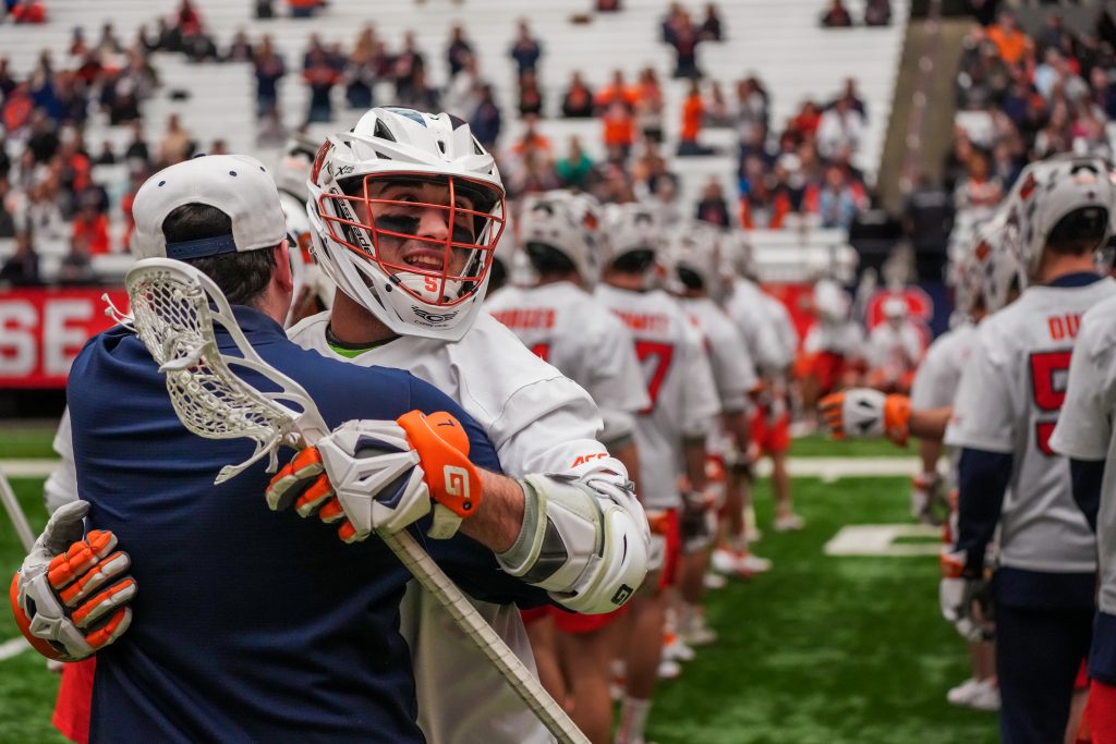 Attacker Owen Hiltz (#77) hugs his coach during pregame lineup announcements before their win against Utah in the dome on Wednesday.