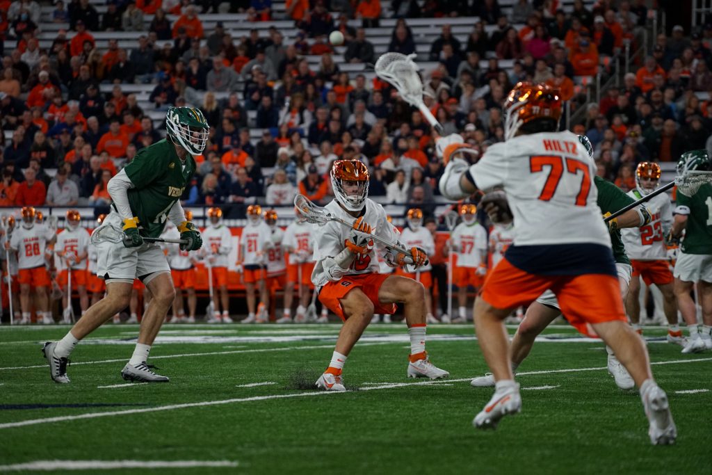 Syracuse attacker Owen Hiltz (#77) makes a pass to midfielder Sam English (#16) against the University of Vermont during the season opener on Feb. 3, 2024, in the JMA Wireless Dome.