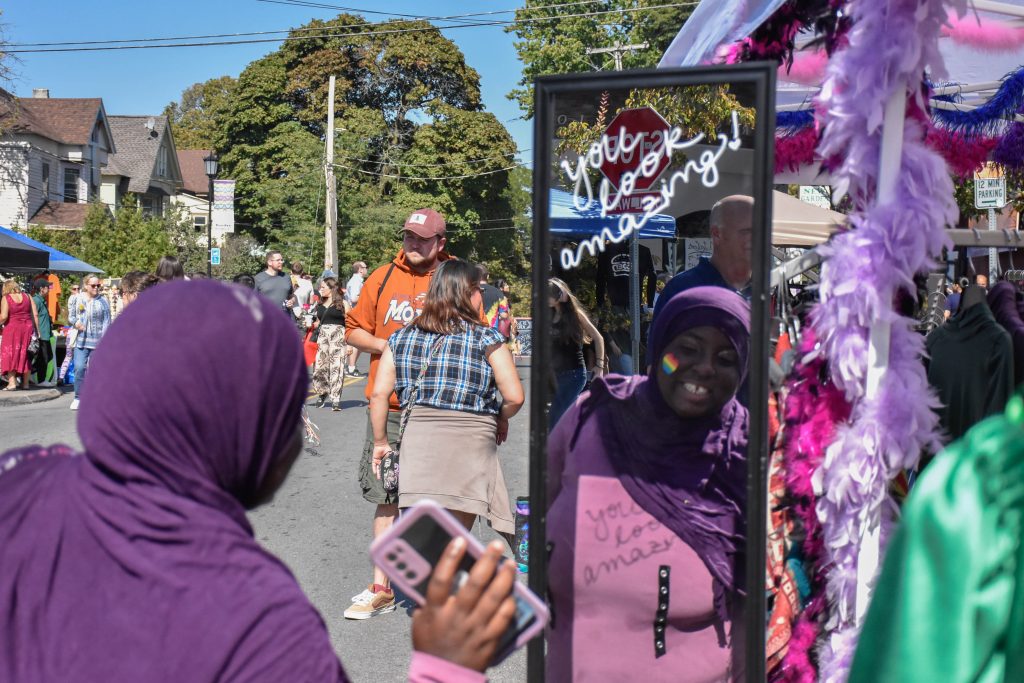 A patron looks at herself in the mirror at a Westcott Street Cultural Fair booth.