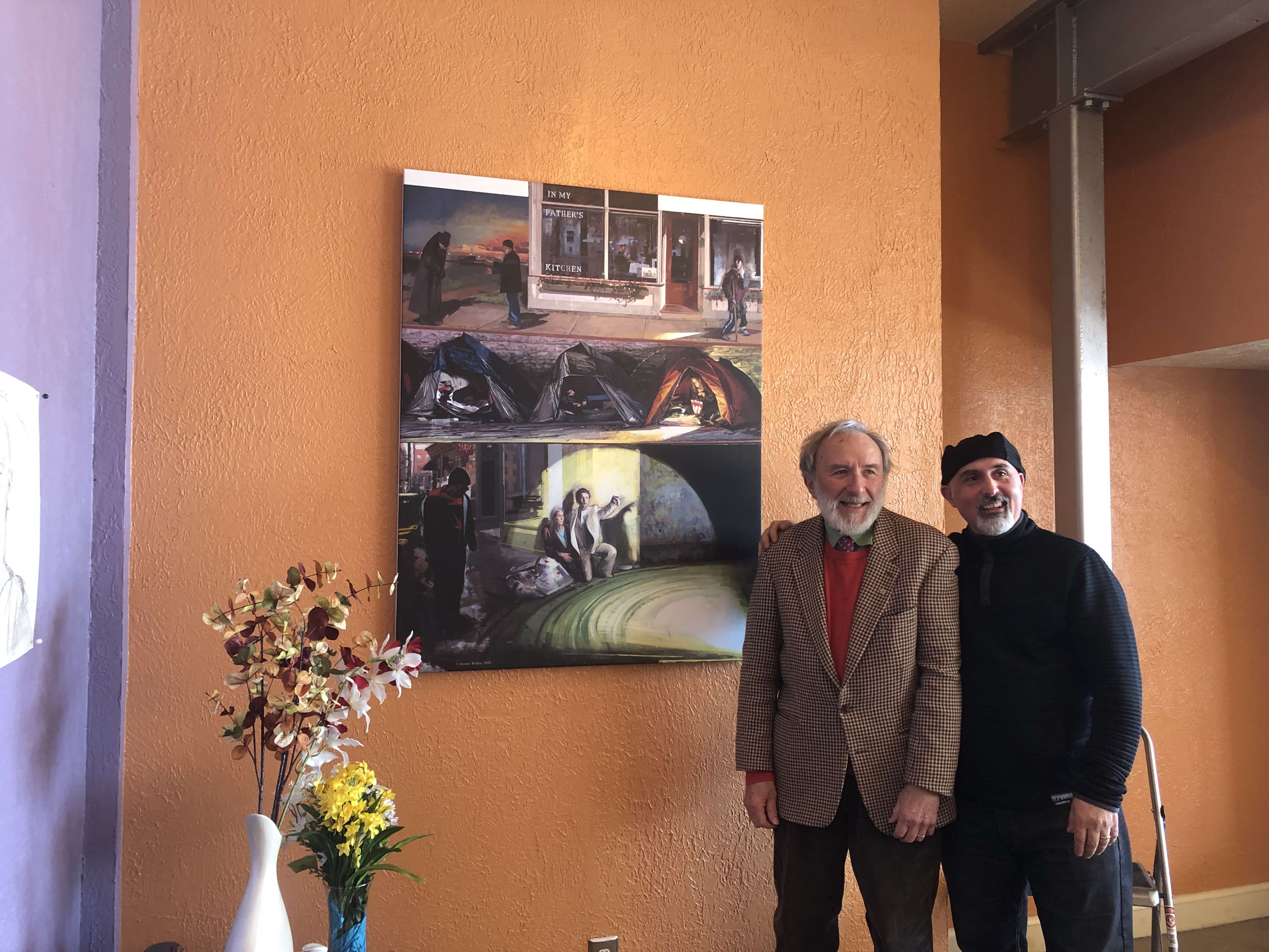 John Tumino, founder of In my Father's Kitchen, (right) stands with Jerome Witkin (left) next to his painting.