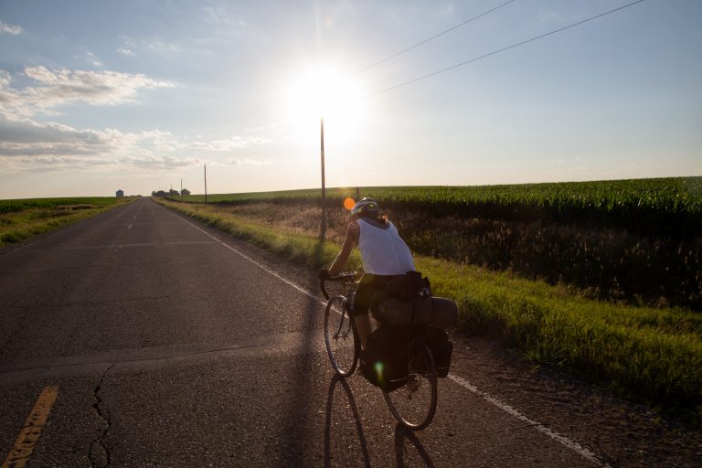 Abby Pershing, 23, biking with her pannier fastened to the back of her bike while riding on the side of I-20 in Iowa.
