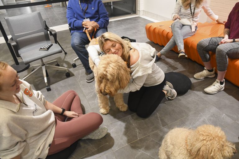 Woman cuddles with dog at a Syracuse University pet therapy room.