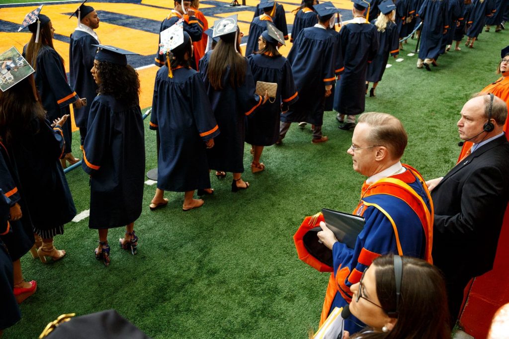 Chancellor Kent Syverud watches as students walk at commencement before the ceremony begins.