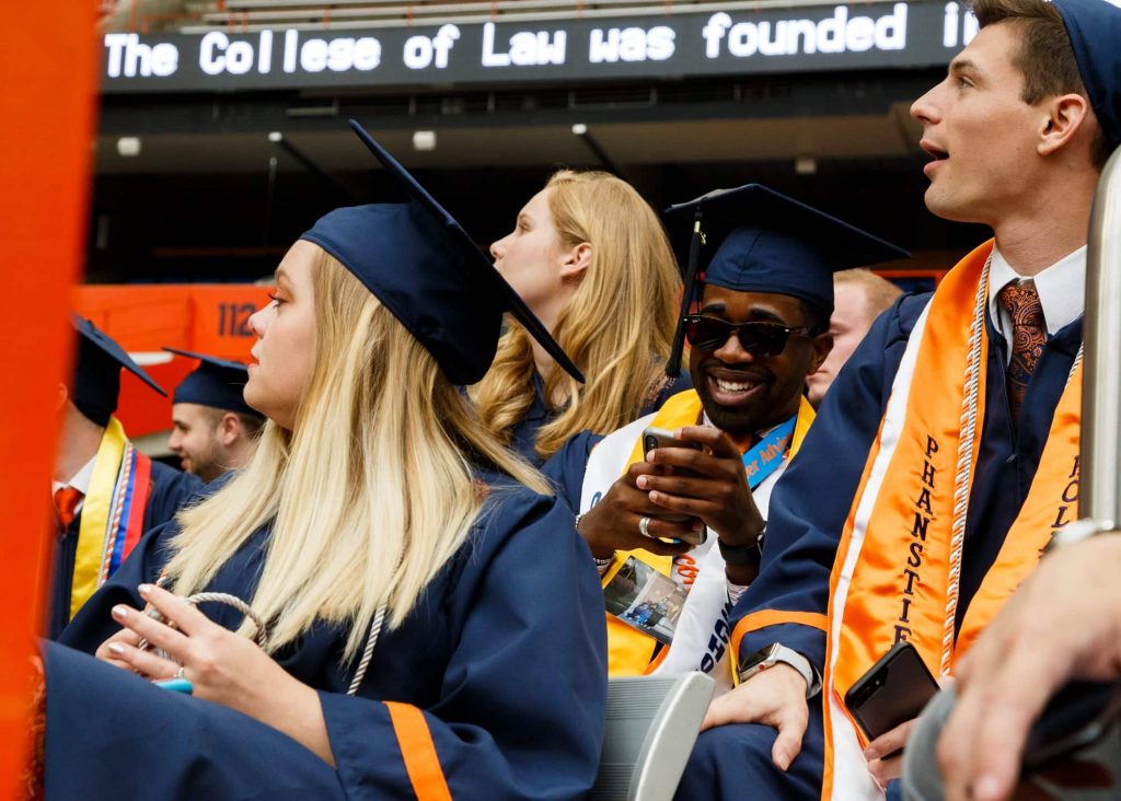 Students wait along the north bleachers of the Carrier Dome before they are seated with other graduates.