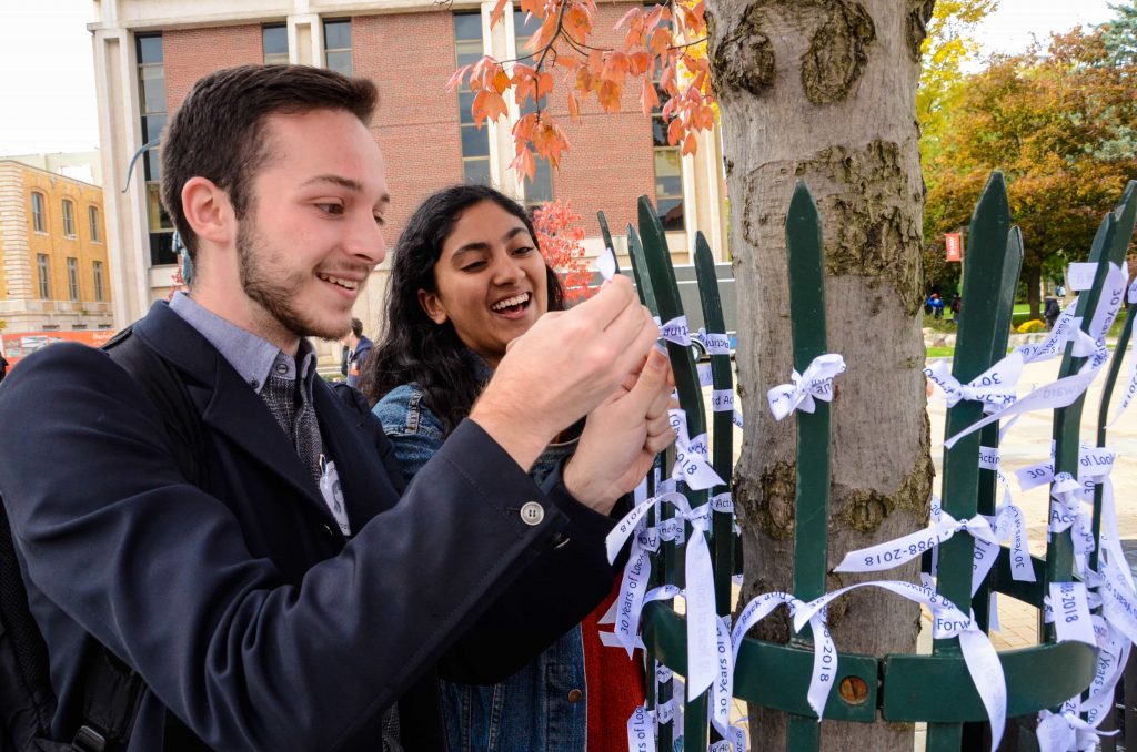 Senior David Robusto and sophomore Sameeha Saied tie their ribbons to a tree for Remembrance Week. 