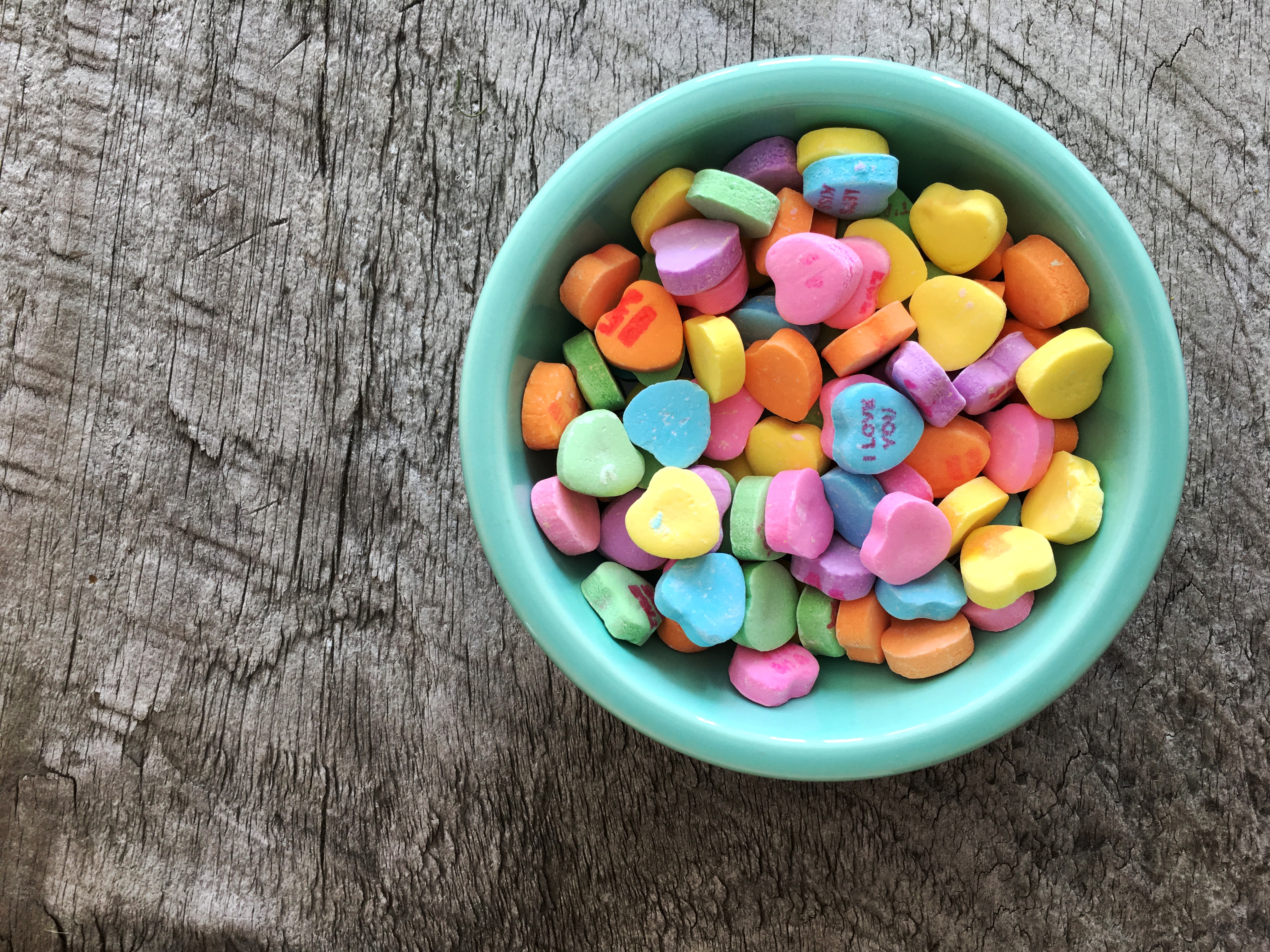 A bowl of Valentine's Day candy sits on a gray surface.