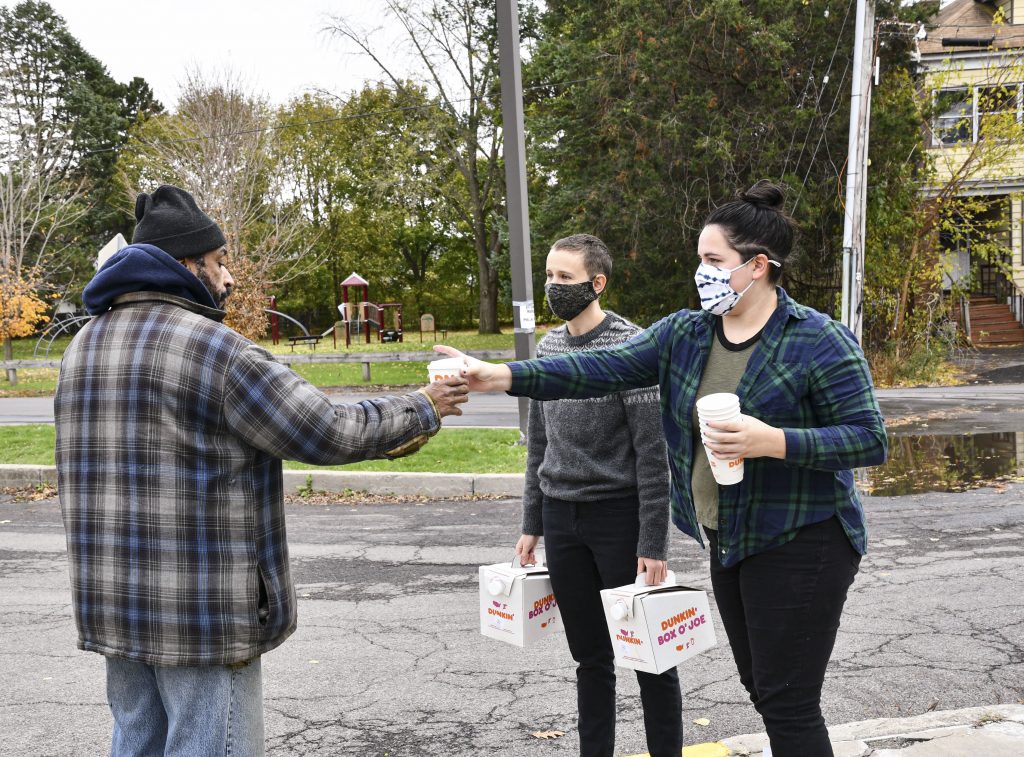 Lydia Dewing (right) and Luca Jurich (left) give a poll worker a cup of coffee on Election Day. According to Dewing, the two wanted to do something nice for voters and poll workers and plan to go to various polling places throughout Syracuse.