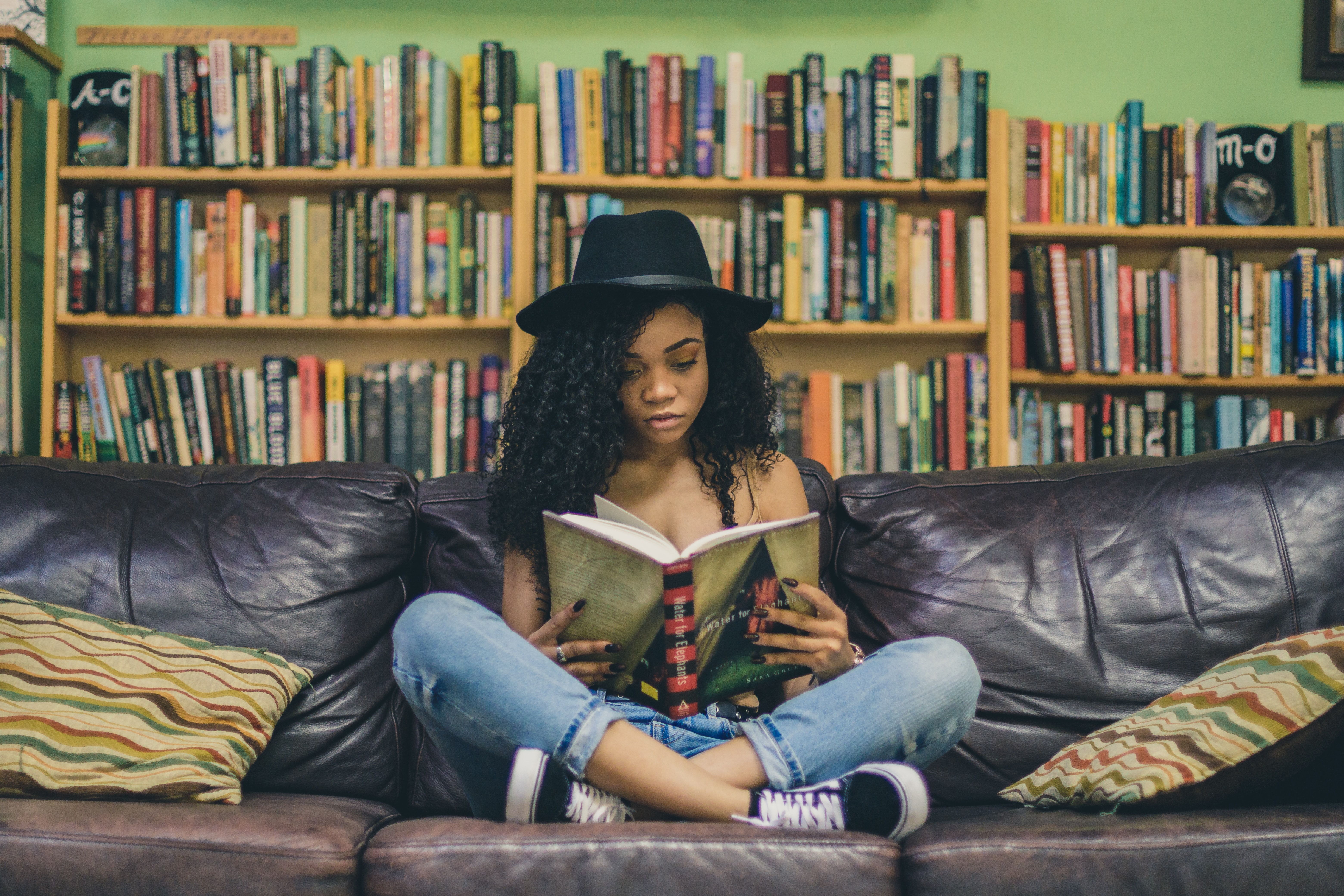 A person sits on a couch reading a book.